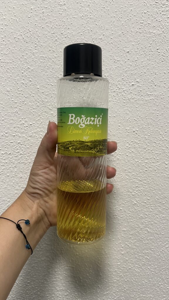 Tyrkisk citron cologne, limon kolonyası i tyrkisk hjem, tyrkisk gæstfrihed og traditioner, citron cologne på sølvbakke, duftende velkomst i tyrkisk kultur, tyrkisk kolonya flaske i entre, tyrkisk tradition med kolonyası, klassisk tyrkisk hjem med gæstepleje, tyrkisk hjem med blomstret sofa og tekande, typisk tyrkisk boligindretning, kolonyası i stue og gæsteværelse, duft og renhed i tyrkiske hjem, citron cologne som tyrkisk symbol, tyrkisk hverdag med gæstekultur, limon cologne og tyrkiske minde