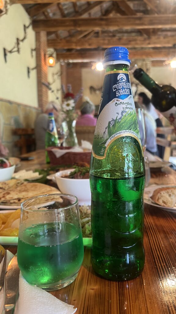 Tarkhun sodavand fra Georgien, georgisk estragon sodavand, grøn sodavand med estragonsmag, georgisk nationaldrik Tarkhuna, forfriskende sodavand fra Kaukasus, georgisk softdrink med urtesmag, Tarkhuna i plastflaske, sød og aromatisk estragon drik, populære drikkevarer i Georgien, Tea Tougaard smager Tarkhun i Georgien, klassisk georgisk drik med naturlige urter, sovjetisk nostalgi sodavand, grøn sodavand serveret til georgisk mad, georgisk estragonbrus, sodavand fra Tbilisi marked