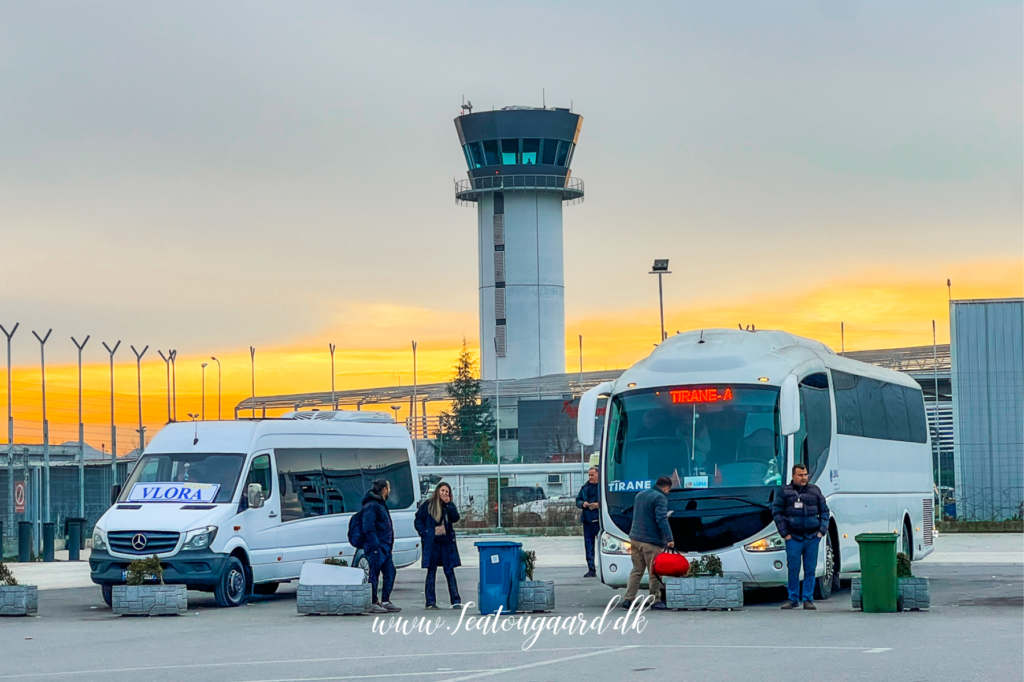 Guide til shuttlebus fra Tirana Lufthavn til Tirana centrum, transport fra Tirana International Airport, hvordan kommer man fra lufthavnen til byen, Rinas Express shuttlebus, offentlig transport i Tirana, praktisk rejsetips til Albanien, pris for shuttlebus Tirana, rejsetid mellem lufthavn og centrum, hvor finder man bussen i lufthavnen, komfortabel og billig transport i Tirana, shuttlebus tidsplan, bus til Skanderbeg-pladsen, hurtig transport til Tirana centrum, lufthavnstransfer i Albanien, ankomstinformation til Tirana, nem rejse fra lufthavn til hotel.