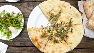 Imeruli Khachapuri, georgisk ostebrød, traditionel georgisk mad, georgisk køkken, Imereti-regionens specialitet, rund khachapuri med ostefyld, populære retter i Georgien, autentisk georgisk bagværk, comfort food fra Kaukasus, must-try mad i Georgien, georgiske brødretter, ostefyldt fladbrød, madoplevelser i Georgien, hjemmelavet khachapuri, georgisk madkultur, lokale specialiteter fra Georgien, Imereti ost, traditionel kaukasisk opskrift.