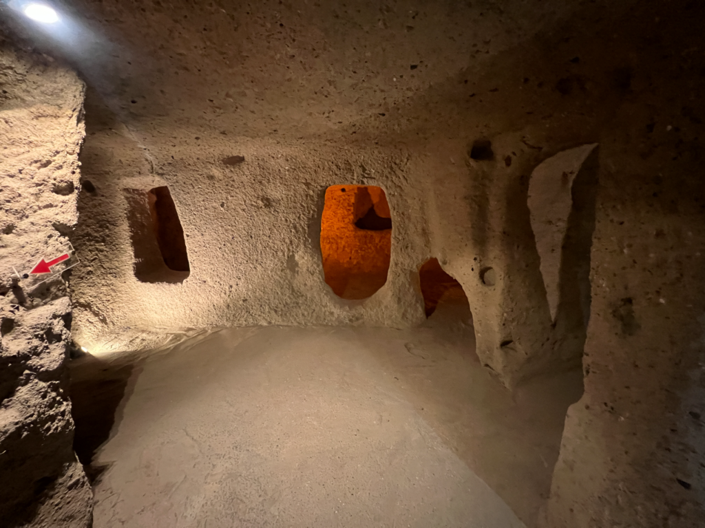 Kaymakli underjordiske by, underjordiske byer i Kappadokien, historiske seværdigheder i Tyrkiet, hulebyer i Anatolien, kristne tilflugtssteder under jorden, oplevelser i Cappadocia, tunneller og labyrinter i klippen, arkæologiske vidundere i Tyrkiet, Kaymakli byens otte niveauer, liv under jorden i oldtiden, stendøre og skjulte forsvarssystemer, must-see i det centrale Tyrkiet, anatolsk historie og kulturarv, underjordisk by med boliger, stalde og kirker, mystik og religion i Cappadocia, rejseoplevelser i Kaymakli.