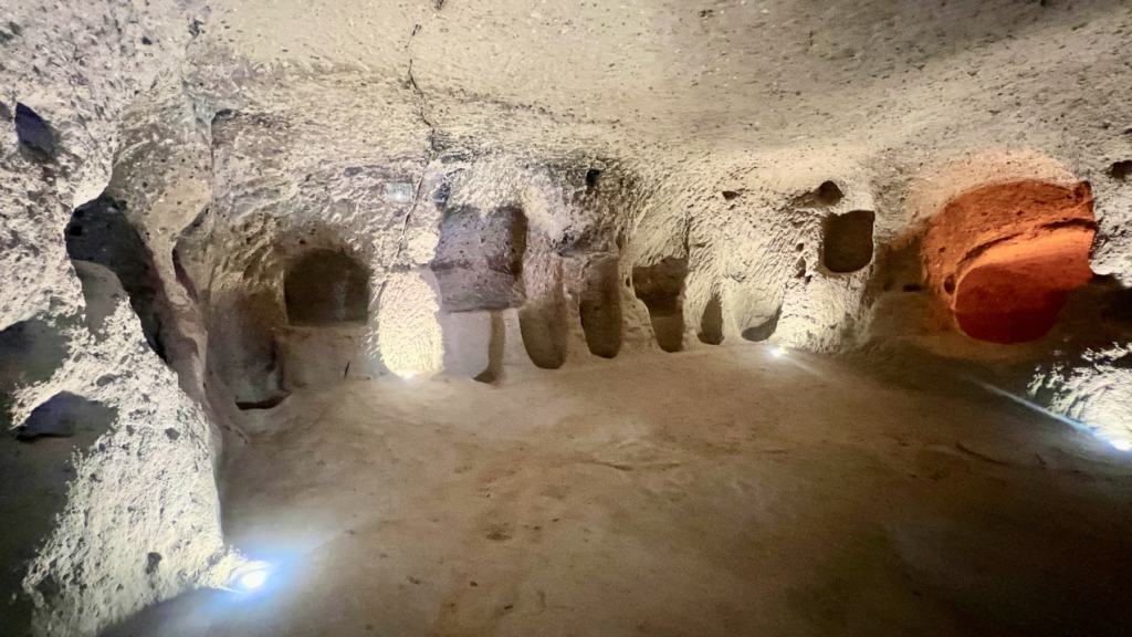 Kaymakli underjordiske by, underjordiske byer i Kappadokien, historiske seværdigheder i Tyrkiet, hulebyer i Anatolien, kristne tilflugtssteder under jorden, oplevelser i Cappadocia, tunneller og labyrinter i klippen, arkæologiske vidundere i Tyrkiet, Kaymakli byens otte niveauer, liv under jorden i oldtiden, stendøre og skjulte forsvarssystemer, must-see i det centrale Tyrkiet, anatolsk historie og kulturarv, underjordisk by med boliger, stalde og kirker, mystik og religion i Cappadocia, rejseoplevelser i Kaymakli.