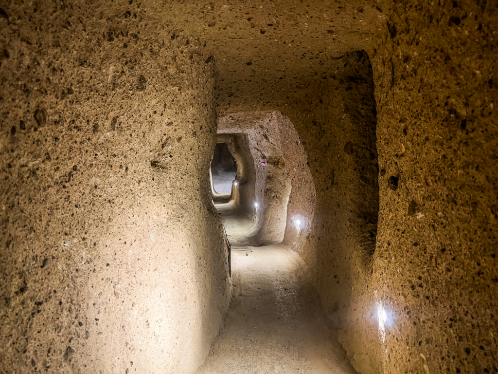 Kaymakli underjordiske by, underjordiske byer i Kappadokien, historiske seværdigheder i Tyrkiet, hulebyer i Anatolien, kristne tilflugtssteder under jorden, oplevelser i Cappadocia, tunneller og labyrinter i klippen, arkæologiske vidundere i Tyrkiet, Kaymakli byens otte niveauer, liv under jorden i oldtiden, stendøre og skjulte forsvarssystemer, must-see i det centrale Tyrkiet, anatolsk historie og kulturarv, underjordisk by med boliger, stalde og kirker, mystik og religion i Cappadocia, rejseoplevelser i Kaymakli
