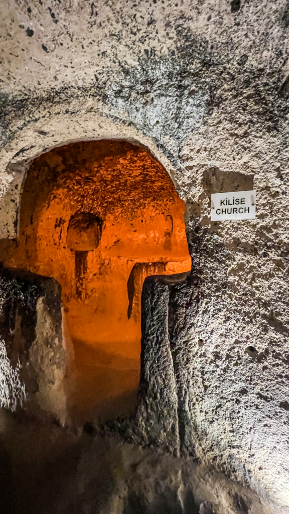 Kaymakli underjordiske by, underjrodisk kirke, underjordiske byer i Kappadokien, historiske seværdigheder i Tyrkiet, hulebyer i Anatolien, kristne tilflugtssteder under jorden, oplevelser i Cappadocia, tunneller og labyrinter i klippen, arkæologiske vidundere i Tyrkiet, Kaymakli byens otte niveauer, liv under jorden i oldtiden, stendøre og skjulte forsvarssystemer, must-see i det centrale Tyrkiet, anatolsk historie og kulturarv, underjordisk by med boliger, stalde og kirker, mystik og religion i Cappadocia, rejseoplevelser i Kaymakli