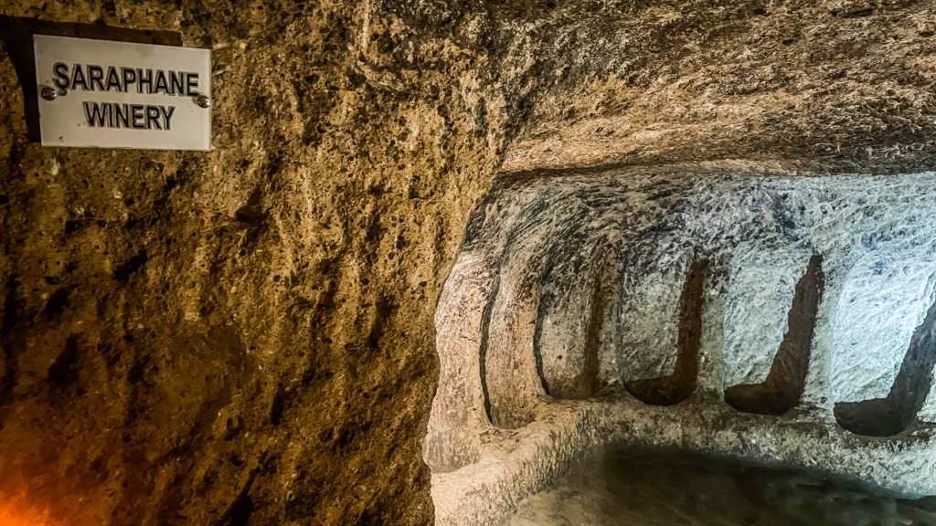 Kaymakli underjordiske by, underjordiske byer i Kappadokien, historiske seværdigheder i Tyrkiet, hulebyer i Anatolien, kristne tilflugtssteder under jorden, oplevelser i Cappadocia, tunneller og labyrinter i klippen, arkæologiske vidundere i Tyrkiet, Kaymakli byens otte niveauer, liv under jorden i oldtiden, stendøre og skjulte forsvarssystemer, must-see i det centrale Tyrkiet, anatolsk historie og kulturarv, underjordisk by med boliger, stalde og kirker, mystik og religion i Cappadocia, vinproduktion Kaymakli, Kappadokien vin, rejseoplevelser i Kaymakli