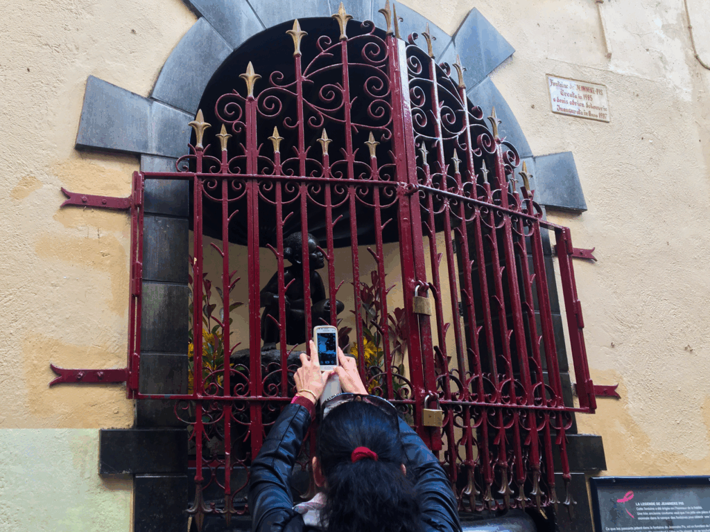 Jeanneke Pis, lille bronzestatue i Bruxelles, pige der tisser, pendant til Manneken Pis, moderne belgisk kunst, humoristisk seværdighed i Belgien, Jeanneke Pis i Bruxelles’ centrum, skjult seværdighed i en gyde, belgisk satire og kultur, sjove oplevelser i Bruxelles, symbol på ligestilling i kunst, quirky Brussels statue, Jeanneke Pis attraktion, must-see i Bruxelles, belgisk tradition i moderne form, unikke statuer i Belgien