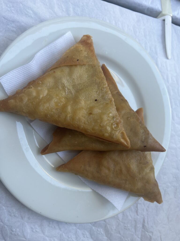 Chamucas Portugal, portugisiske chamucas, chamuca snacks, portugisiske specialiteter, portugisisk street food, portugisisk mad med indiske rødder, krydrede snacks fra Portugal, portugisisk madguide, mad du skal smage i Portugal, traditionelle portugisiske snacks, portugisiske forretter, mad fra Goa og Mozambique i Portugal, krydret trekantet dej snack, portugisisk fusionkøkken, eksotisk mad i Portugal, madrejse gennem Portugal, chamuca med kød eller grønt, portugisisk indflydelse fra kolonitiden, portugisisk madkultur, krydret portugisisk snack