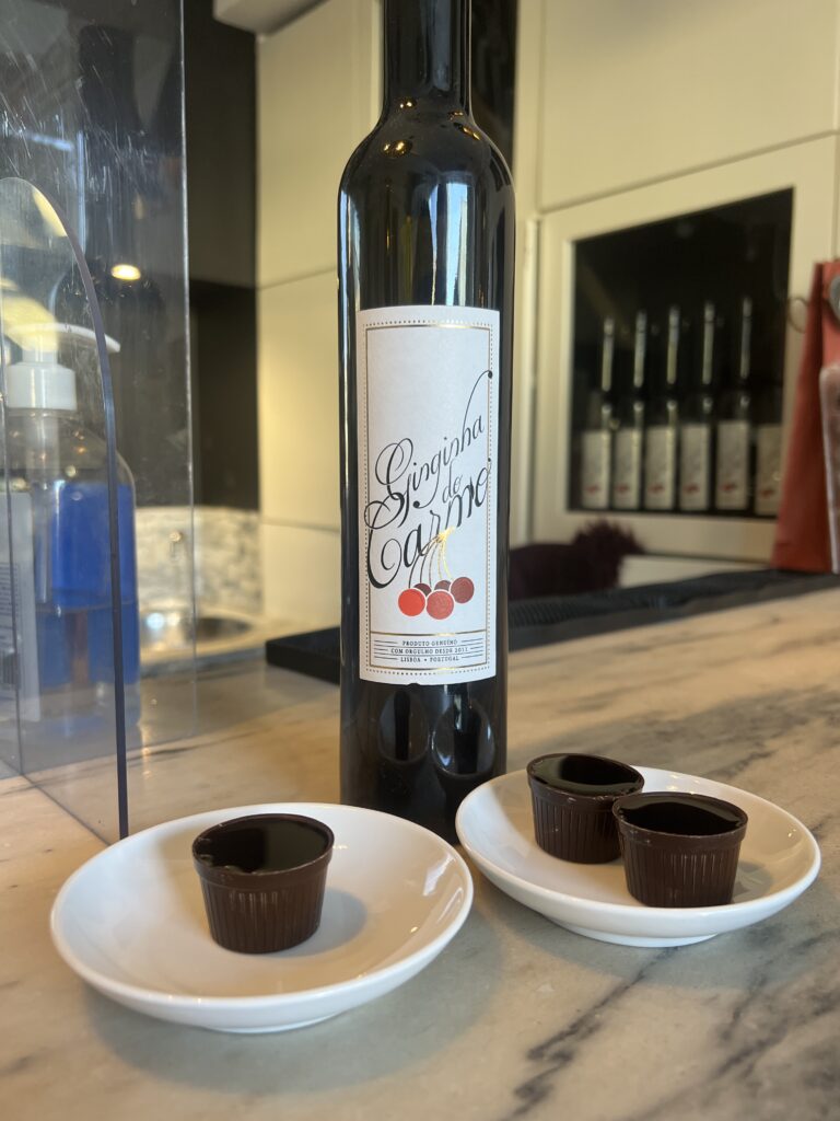 Ginjinha shots, portugisisk kirsebærlikør, drikkevarer fra Portugal, traditionelle portugisiske shots, Ginja de Lisboa, Ginjinha Espinheira, Ginjinha-servet i chokoladekop, likør fra Portugal, portugisiske specialiteter, must-try drikke i Portugal, typiske portugisiske drikkevarer, kirsebærshot fra Portugal, lokal portugisisk kultur, autentiske oplevelser i Lissabon, sød kirsebærlikør, shots i Portugal, portugisisk mad og drikke, drikke du skal smage i Portugal, portugisisk spiritus, street drinks i Lissabon, oplev ginjinha i Portugal